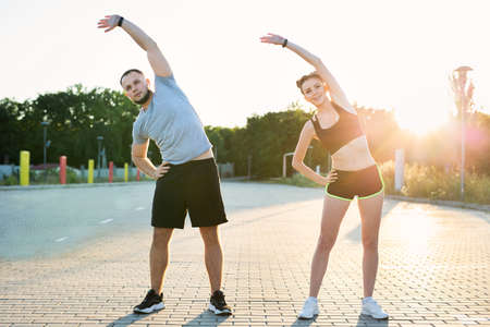 Young couple trains outdoors in a Park in the summer at sunset.の写真素材