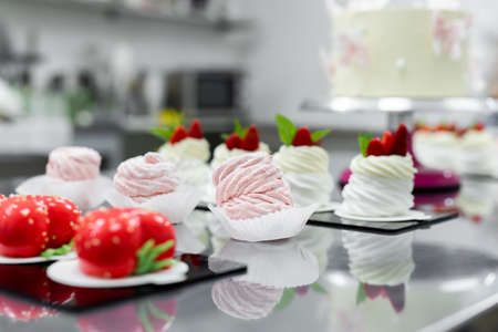 Pavlova meringue, marshmallows and mousse cake on the table in the pastry shopの写真素材