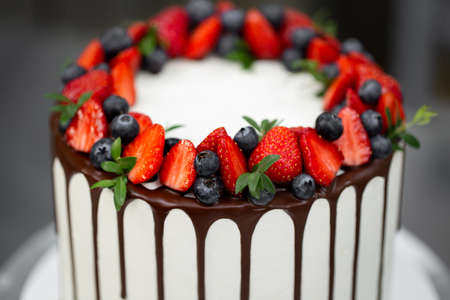 Cake with chocolate streaks and berries in the kitchen.
