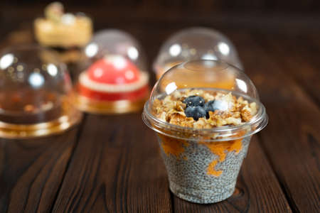 Variety of desserts in cups, including chia pudding on a brown wooden background