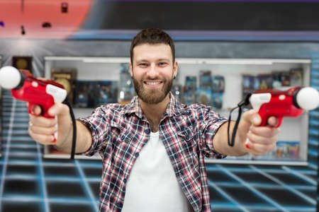 Young man plays on a video games console, an emotional gamer shoots a game using a gun controller in...