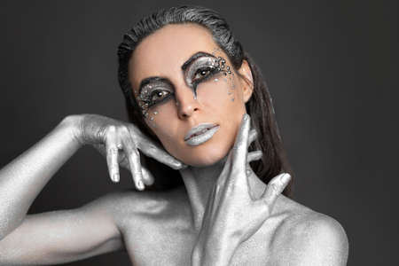 Portrait of a beautiful woman with silver paint on her skin and hairの写真素材