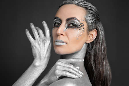 Portrait of a beautiful woman with silver paint on her skin and hair