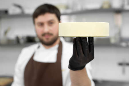 Male pastry chef holds a frozen mousse cake and prepares it for the icingの写真素材