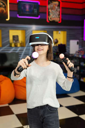 Child, a teenage girl playing on a game console in virtual reality glasses shooting a game with a...