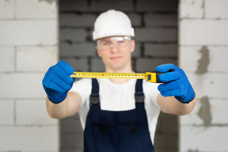Portrait of a male construction worker in a helmet holding a roulette wheelの写真素材