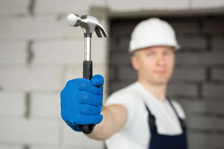 Male construction worker wearing a helmet with a hammer.の写真素材