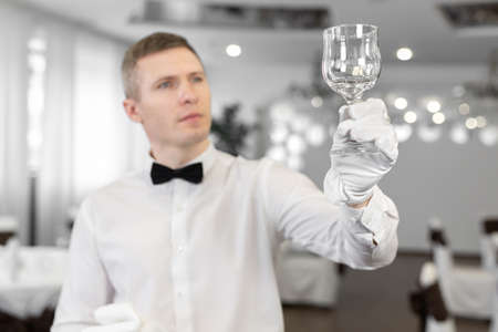 Male waiter in white gloves rubs a wine glass.の写真素材