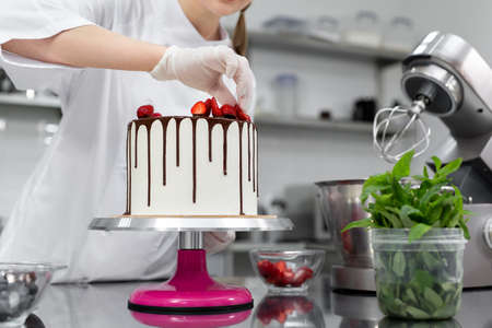 Pastry chef decorates the cake with chocolate streaks of strawberriesの写真素材