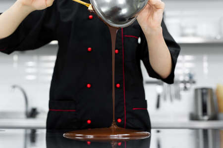 The pastry chef pours hot chocolate on a cold table for temperingの写真素材