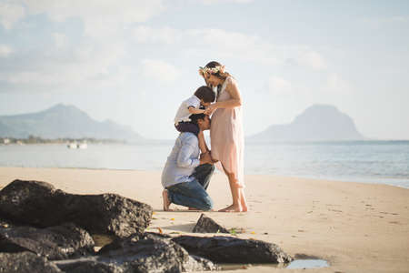 Pregnant woman, baby and mixed race man on the beach.の写真素材