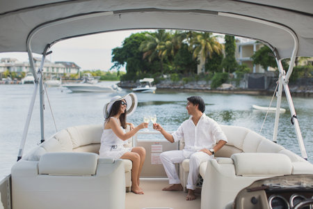 Smiling young couple holding glasses with champagne and looking at each other while sitting on the...