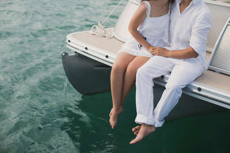 Young couple is sailing on a yacht in the Indian Ocean. Man and woman sit on the edge of the yacht.の写真素材