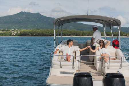 Young couple navigating on a yacht in Indian ocean. Handsome man and woman on deck of yacht lie on...