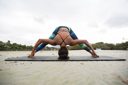 Young woman practices yoga on the shore of the Indian ocean in Mauritius and mountain in the...