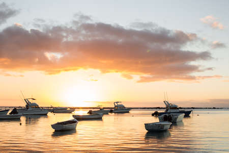 Small boats in the ocean at sunsetの写真素材