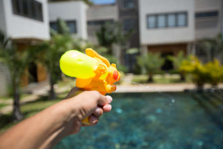 Man fires a water gun into a woman, while having fun in the poolの写真素材