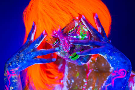 Neon Woman dancing. Fashion model woman in neon light, portrait of beautiful model with fluorescent make-up, Art design of female disco dancer posing in UV, colorful make up.の写真素材