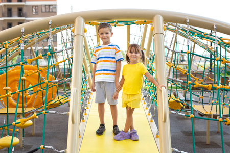 Children, brother and sister, play on a modern playground and climb a giant climbing web.の写真素材