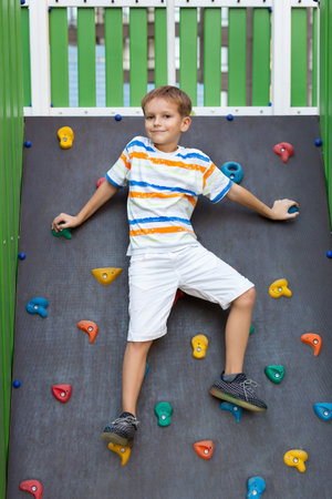 A little boy climbs a climbing wall on a modern playground.の写真素材