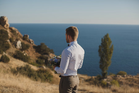 The groom is waiting for the bride on the background of the blue seaの写真素材