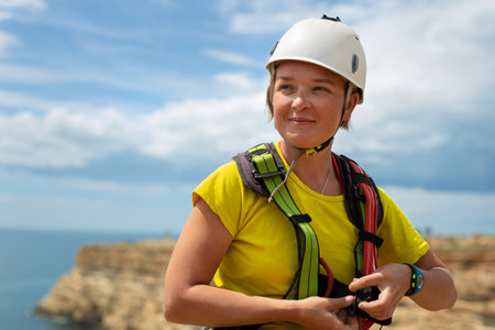 Woman in a protective helmet checks equipment and insurance before jumping off a cliff on the track.の写真素材