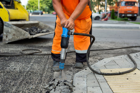 Road worker breaking street asphalt with jackhammer.の写真素材