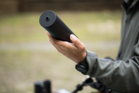Military holds a pistol with a silencer.