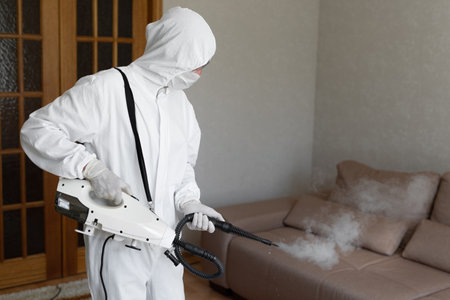 Virologist in protective hazmat suit conducts disinfections of surfaces in publicの写真素材