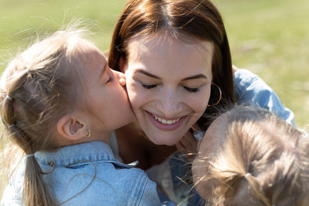 Close-up portrait of a mother and twin daughters hugging and smiling in nature