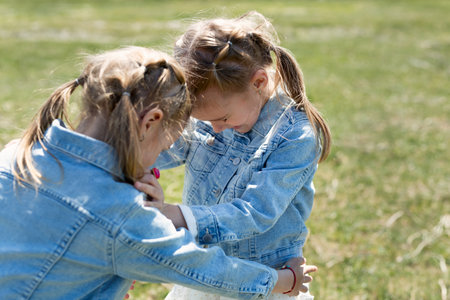 Two little twin sisters run and spin in the meadowの写真素材