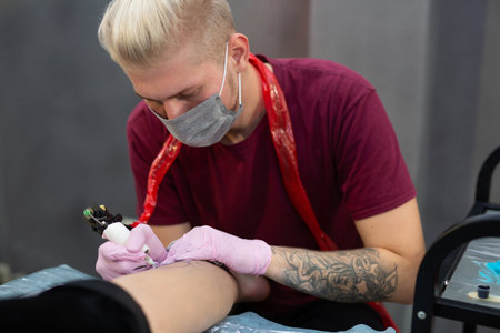 Professional tattoo artist a man in pink gloves makes a tattoo in the salon.の写真素材
