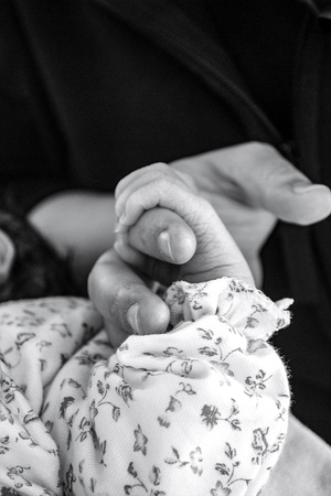 Little baby holding the finger of a young womanの写真素材