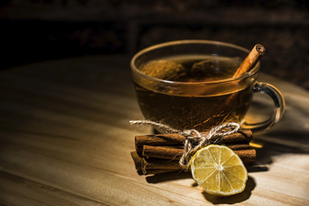 A cup of tea with a cinnamon sticks and a lemon slice on a wooden table, close upの写真素材