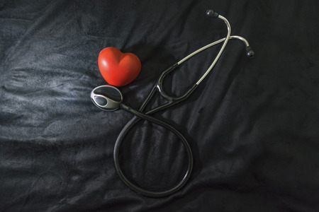 Stethoscope and heart figure on black background, indoorの写真素材