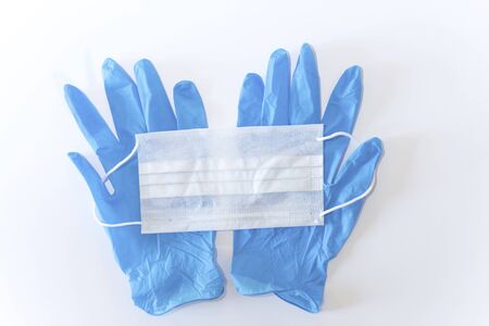 A pair of latex gloves and a white surgical mask on a white background, isolated, above vantage pointの写真素材