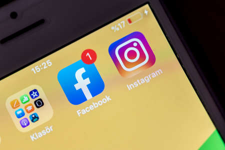 Facebook and Instagram application's logos and low battery warning on a smart phone's screen, close...