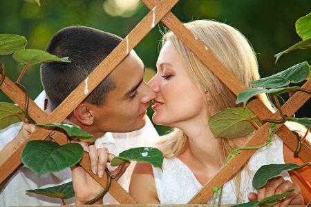 Young happy couple kissing at wooden lattice の写真素材