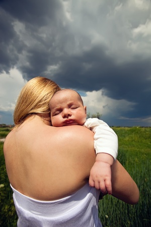 Baby sleeping on mother s shoulder against rural backgroundの写真素材