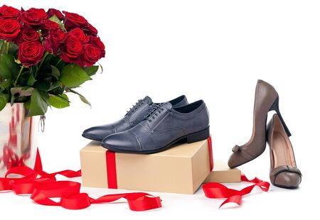 Female and male shoes on gift boxes and bunch of roses over white background の写真素材