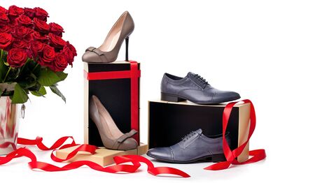 Female and male shoes on gift boxes and bunch of roses over white background の写真素材