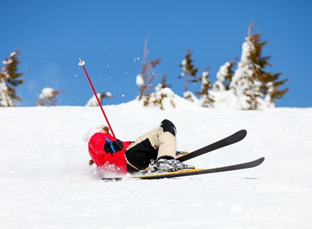 Girl skier falling down white on mountain slope の写真素材