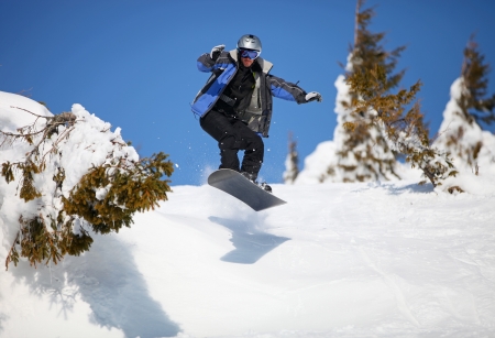 Snowboarder jumping on mountain slope の写真素材