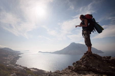 Young man standing on a rock against picturesque view of sea の写真素材