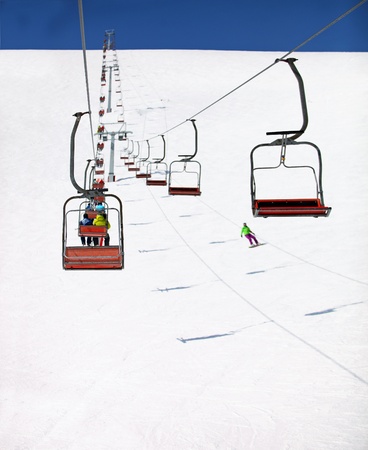 View of skiing resort with chairlifts going to the the top of a slope on a sunny day 
