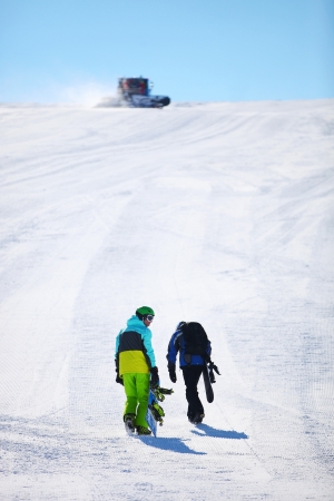 	Two snowboarders walking up slopeの写真素材