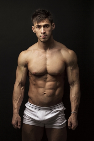 Portrait of muscular young man over black backgroundの写真素材
