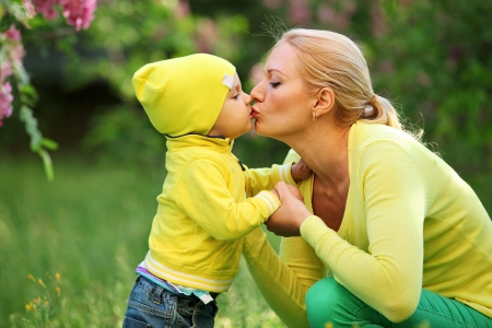 Little boy kissing his young mother outdoorsの写真素材
