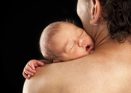 Newborn boy sleeping on his dad s shoulder over blackの写真素材