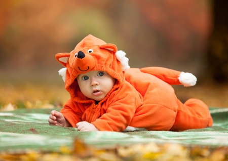 Cute baby boy dressed in fox costume in autumn parkの写真素材